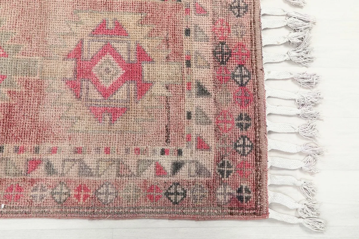 Close-up of the rug's end with geometric border details and fringe.