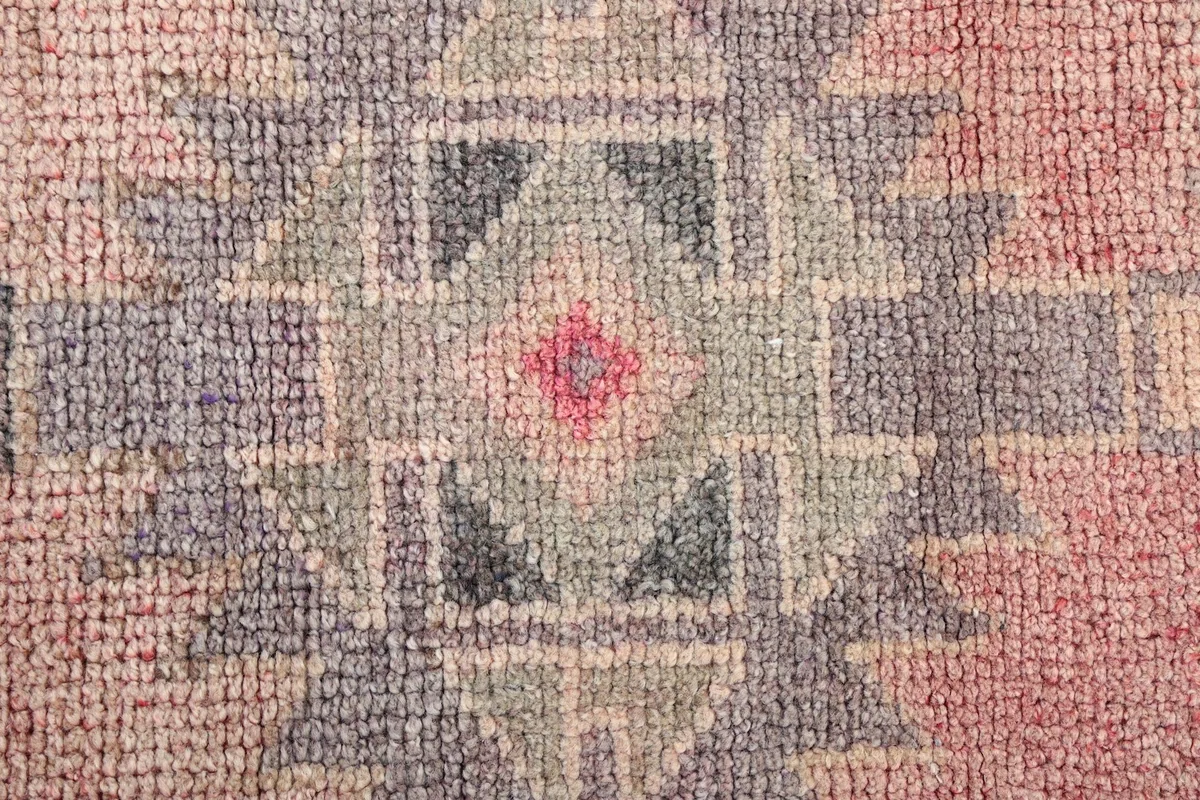 Extreme close-up showing the low wool pile and intricate knotting of the rug.