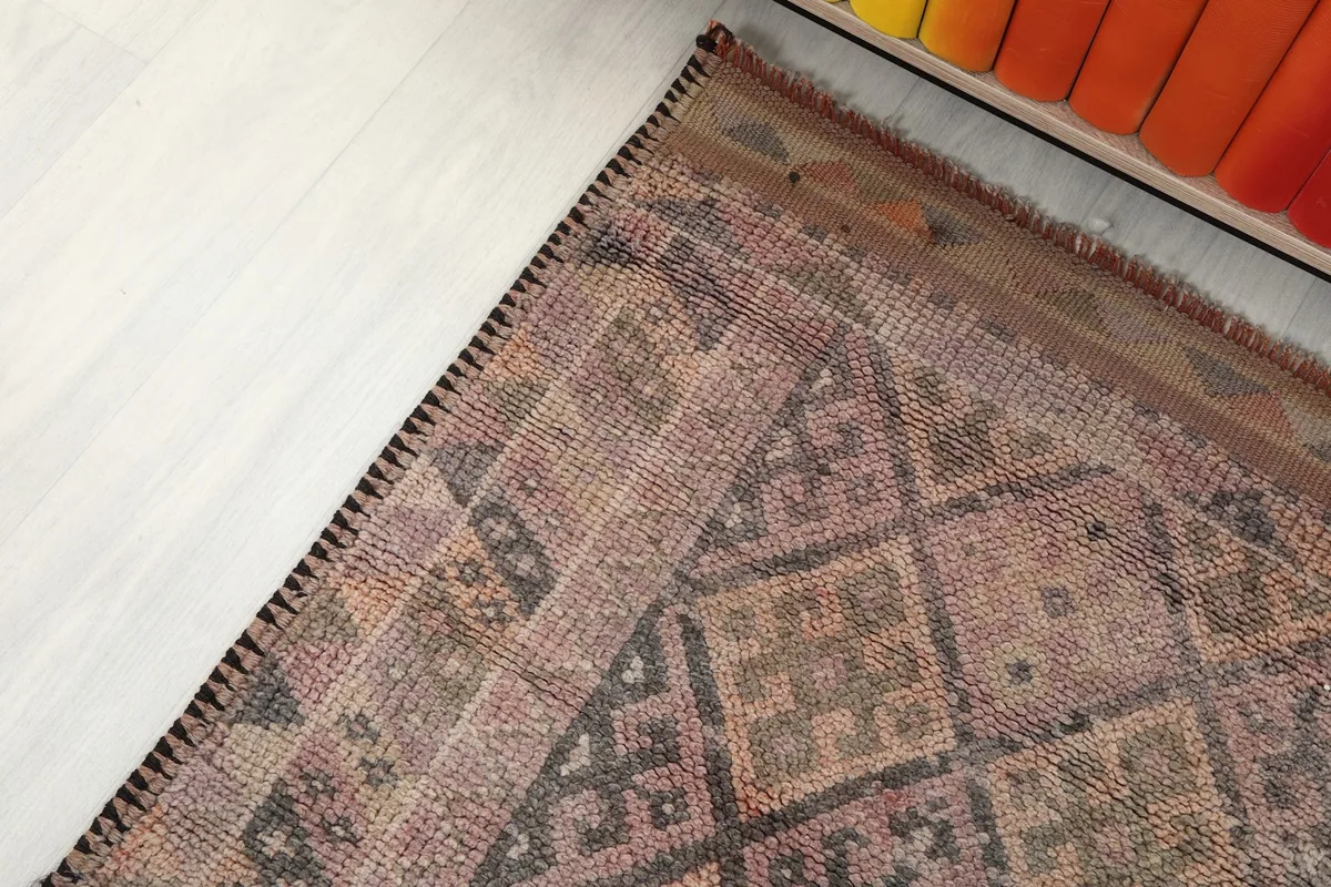 Angled detail shot of the rug's pattern near a corner, showing the border design