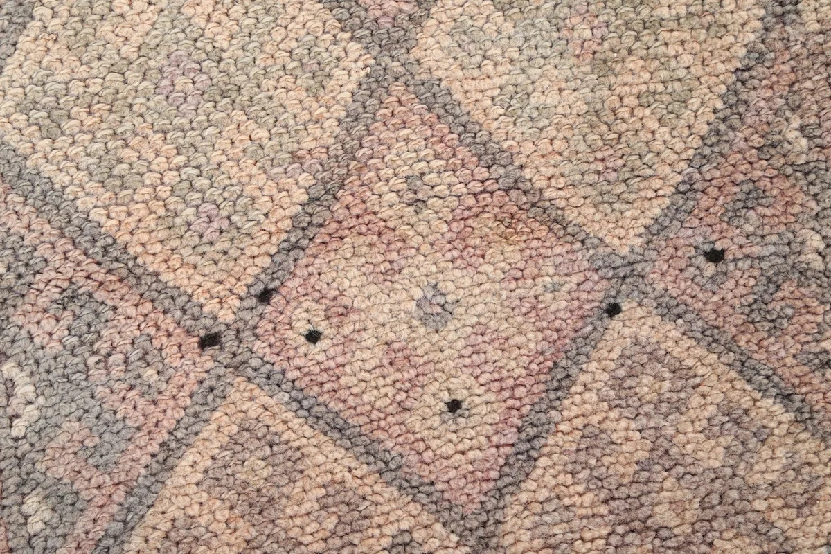 Extreme close-up of the low wool pile, revealing the intricate knots and faded colors