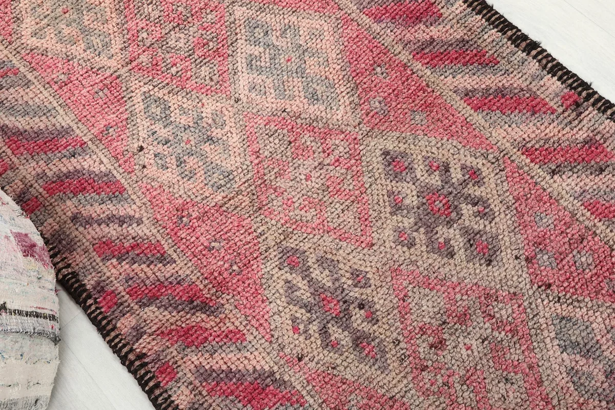 Angled shot highlighting the geometric diamond motifs and color variations on the faded red runner.