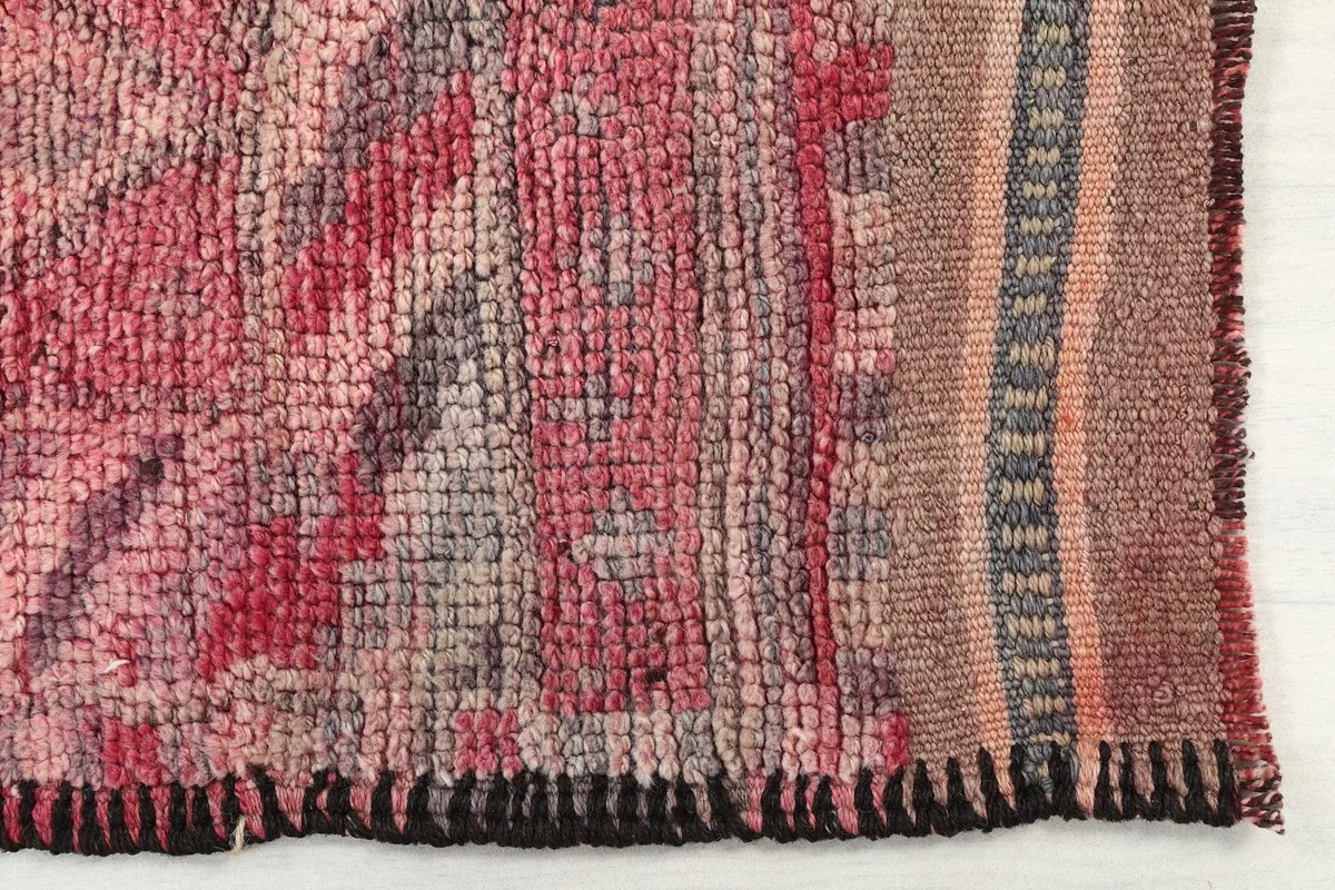 Detailed view of the hand-knotted wool pile and weave texture of the faded red rug.