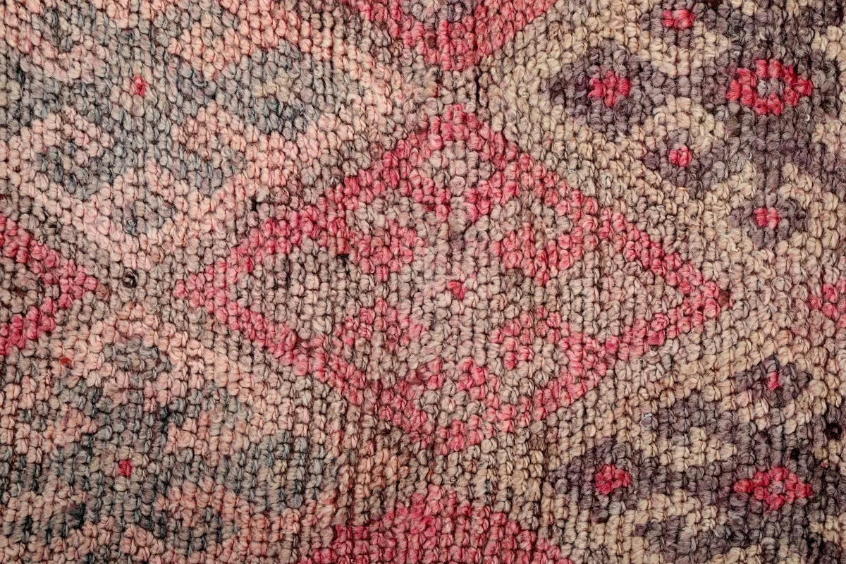 Macro detail of a central geometric diamond motif and surrounding tribal elements in red and gray.