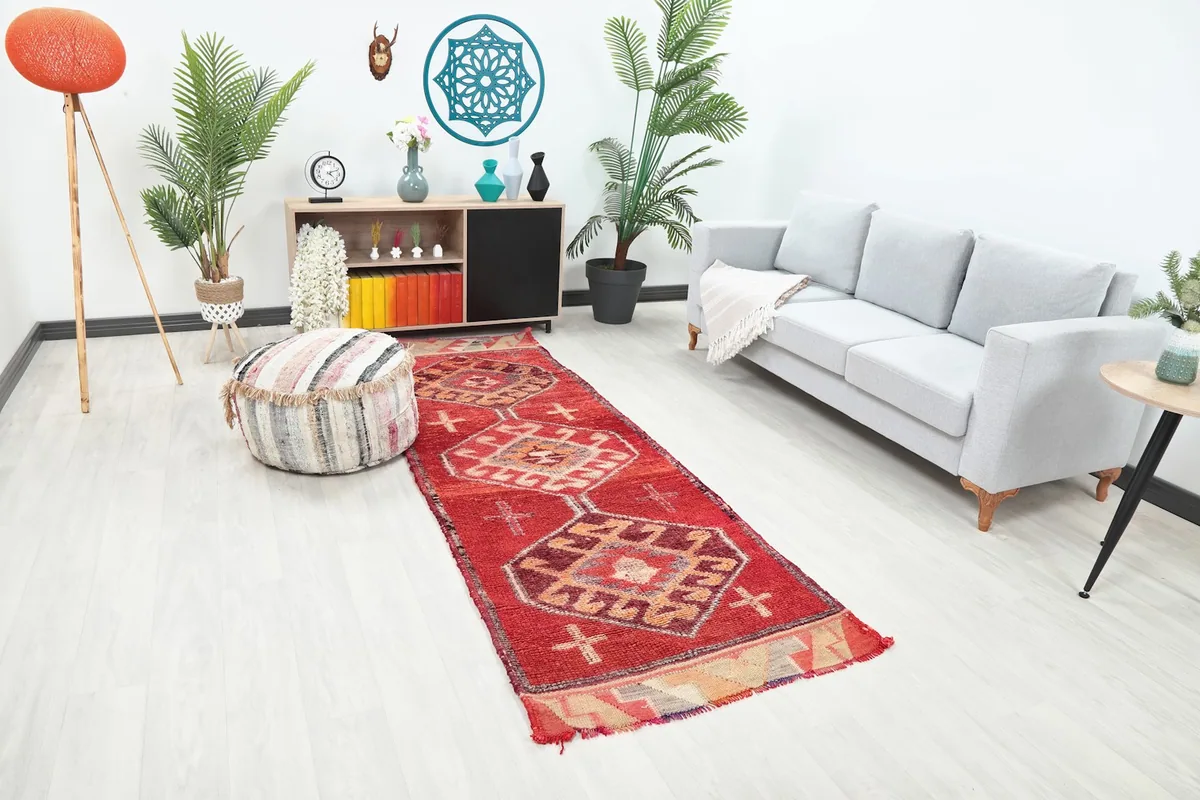 Angle view of the red runner rug in a room with a light gray sofa and decorative elements.