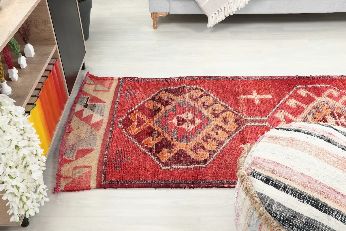 Overhead view of the red runner rug extending through a living space with a pouf in the foreground.