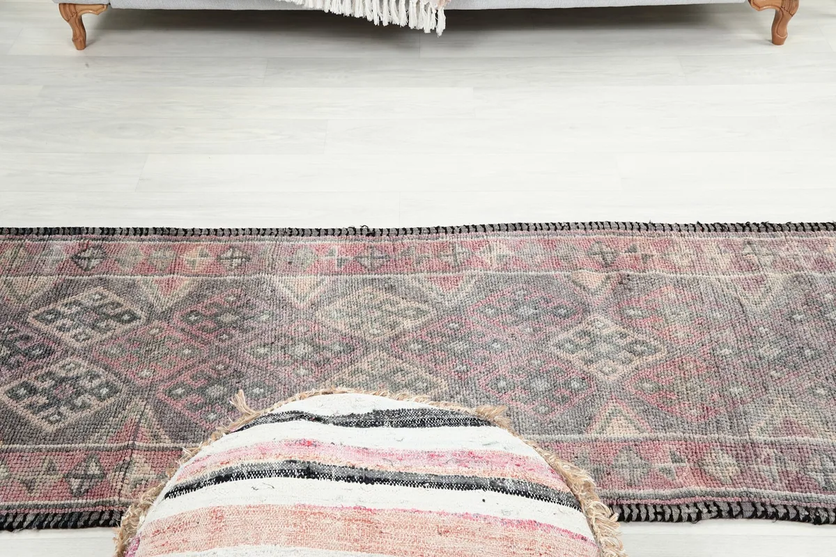 Runner rug in a room setting, with a decorative pouf in the foreground.