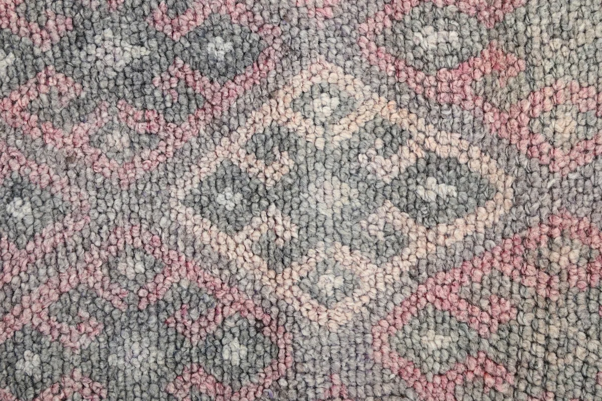 Close-up of the low wool pile, showing the texture and color blend of gray and rose threads.