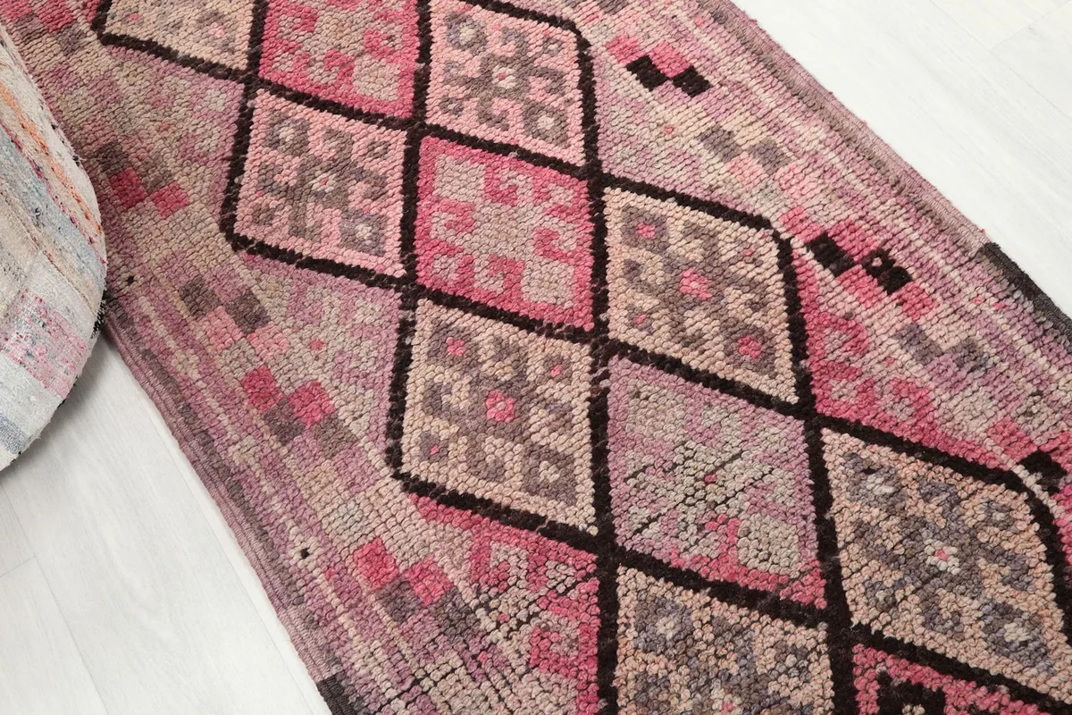Angled view showcasing the pink and gray diamond motifs along the length of the runner rug
