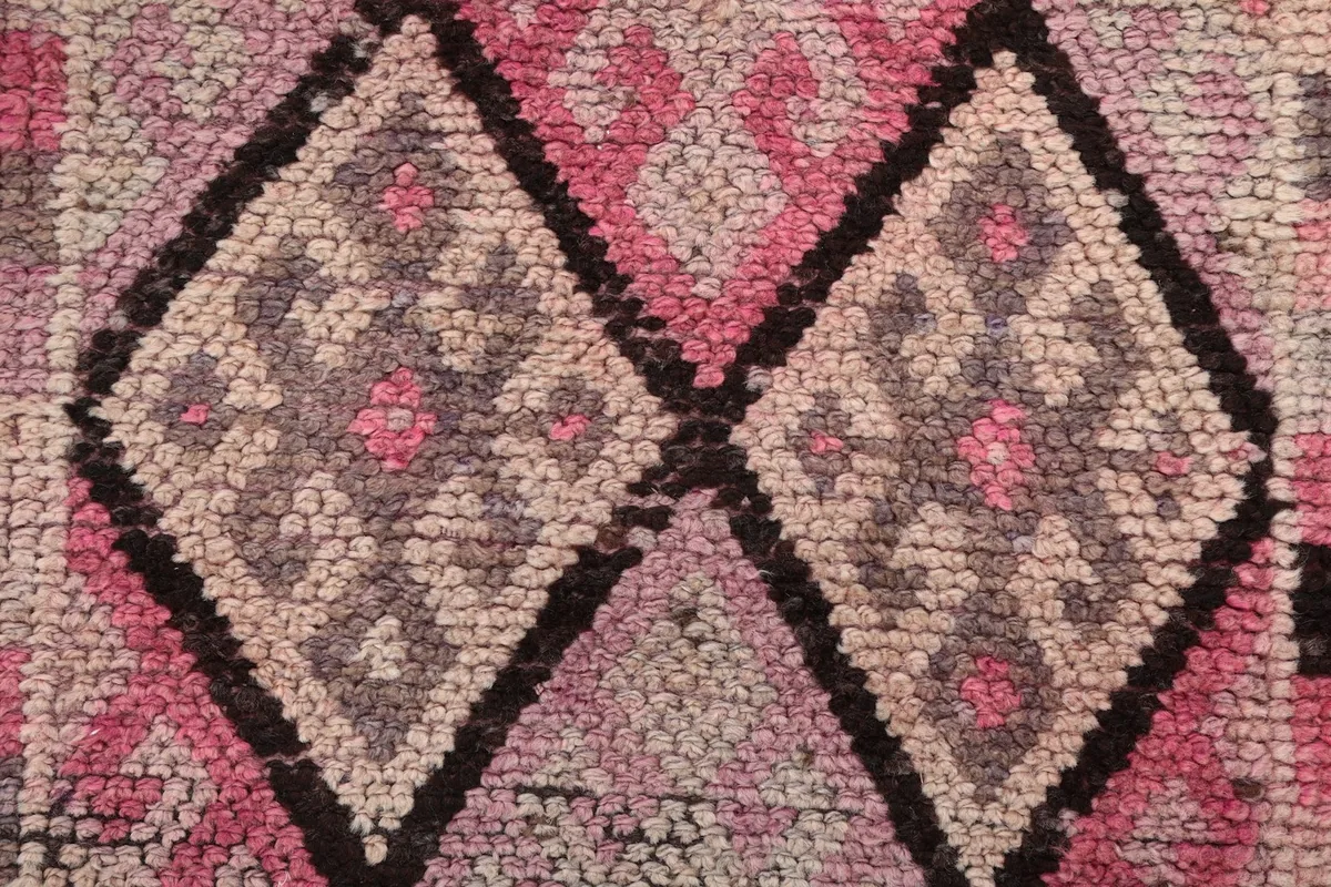 Close-up of the wool pile showing the texture and colors of the pink, gray, and black geometric design