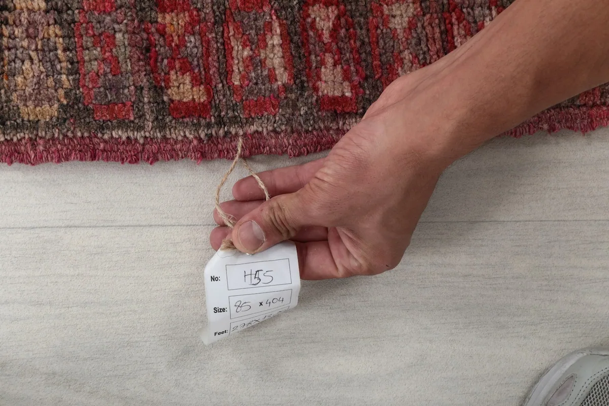 Hand holding the product tag, indicating the rug's unique item number and size