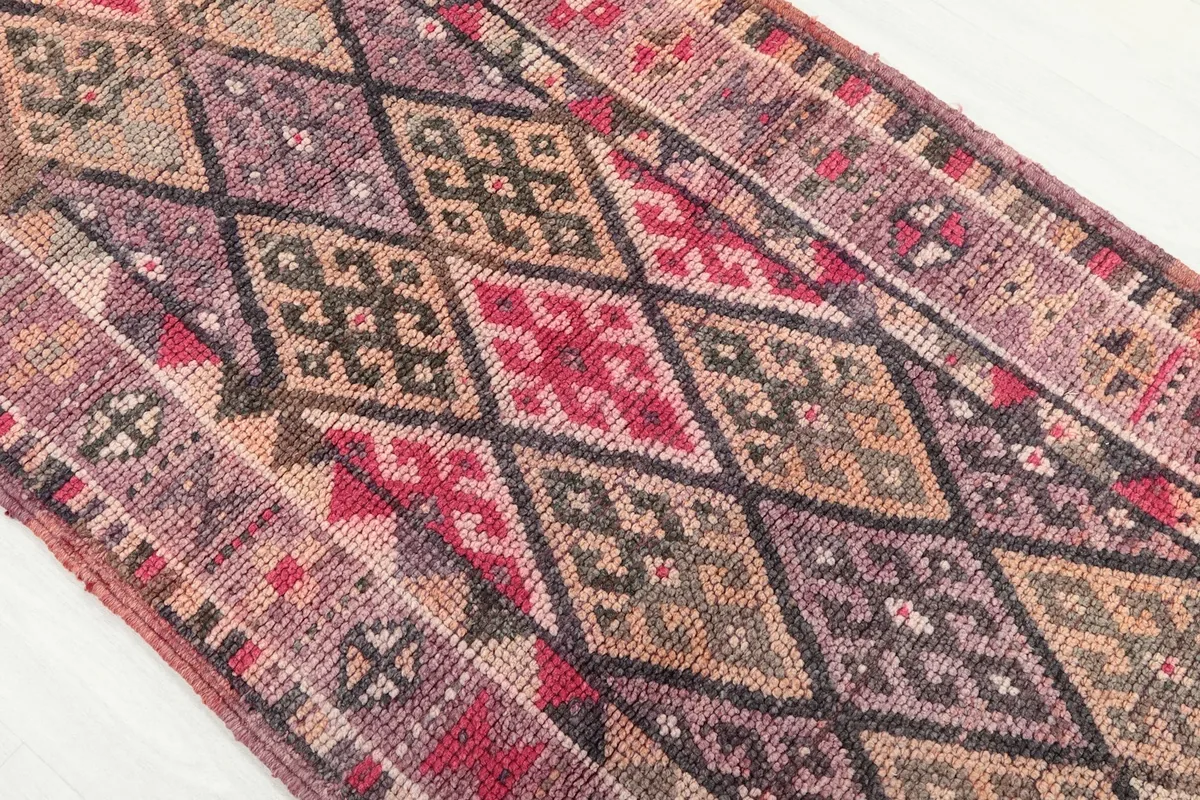 Detailed view of the geometric diamond motifs and color variations in the rug's center