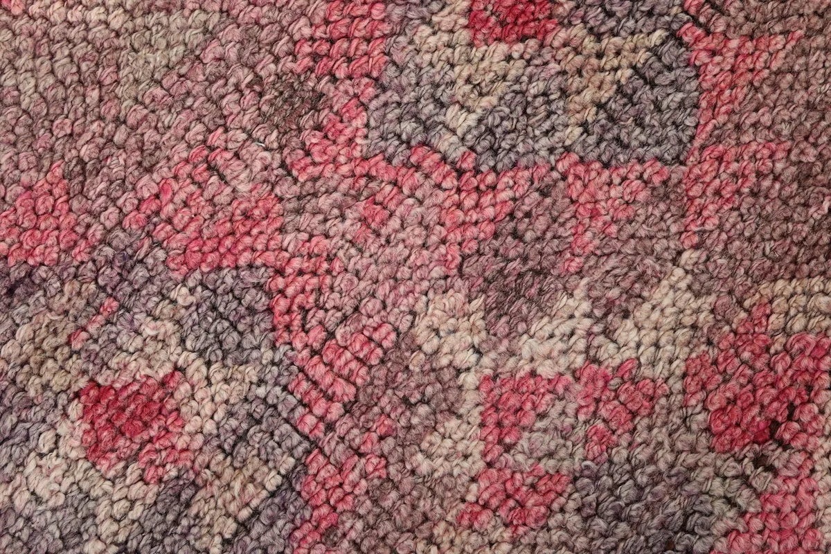 Macro shot of the rug's low wool pile, revealing the intricate knotting and color variations of rose and gray.