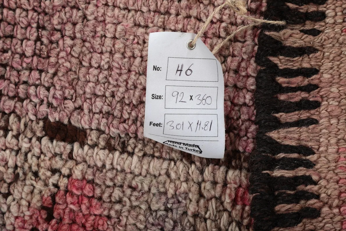 Detail of the rug's surface with an attached product tag displaying its size in cm and feet.