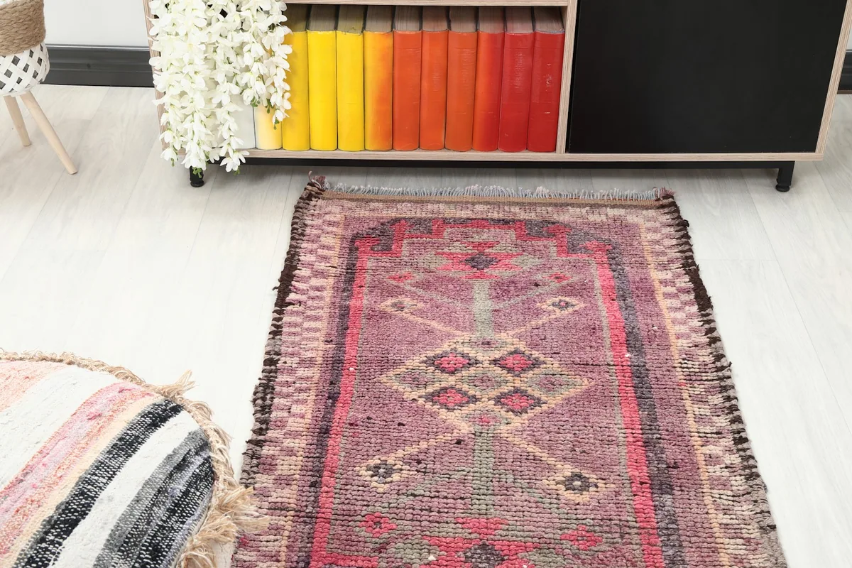 Overhead view of one end of the rose runner rug in a room, next to a colorful bookshelf.