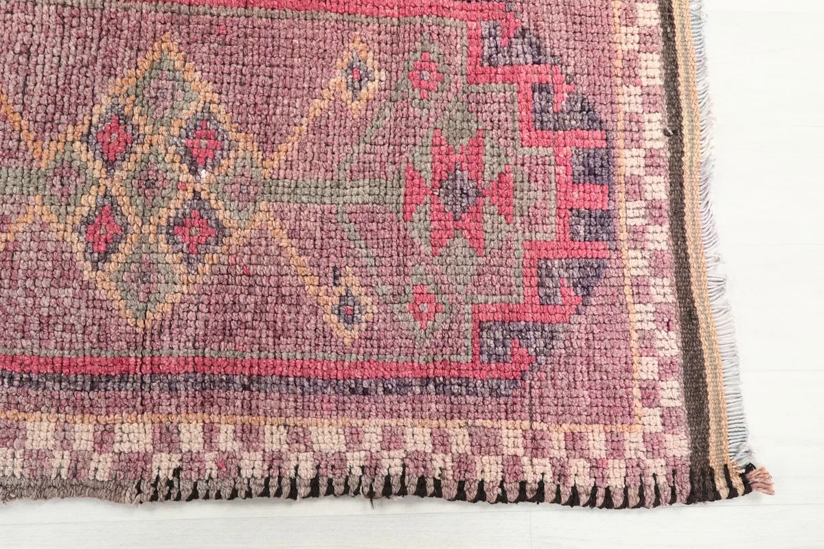 Detailed view of the rose rug's border and a section of the geometric pattern with red and beige tones.