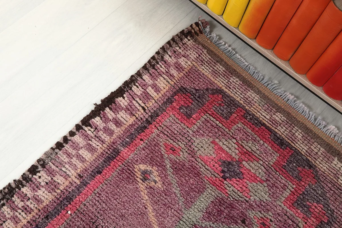 Close-up of the rug's border design, fringe, and a corner showing the hand-knotted details.