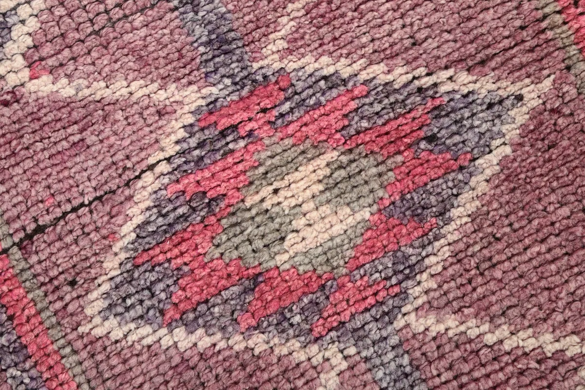 Macro view of the hand-knotted wool pile, showing the texture and colors of a geometric motif.