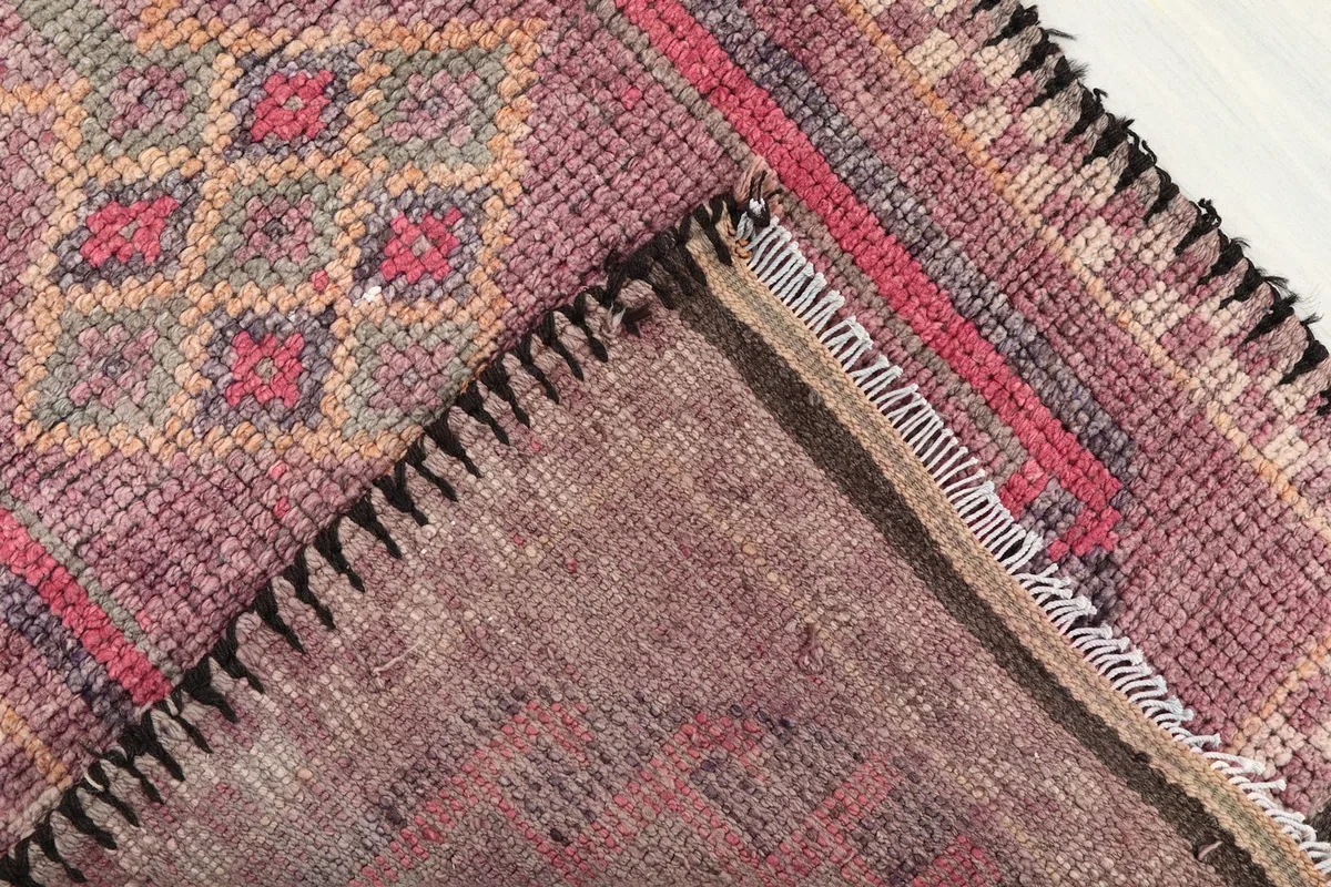 Underside view of the rug, revealing the cotton foundation and the reverse of the hand-knotted wool pile.