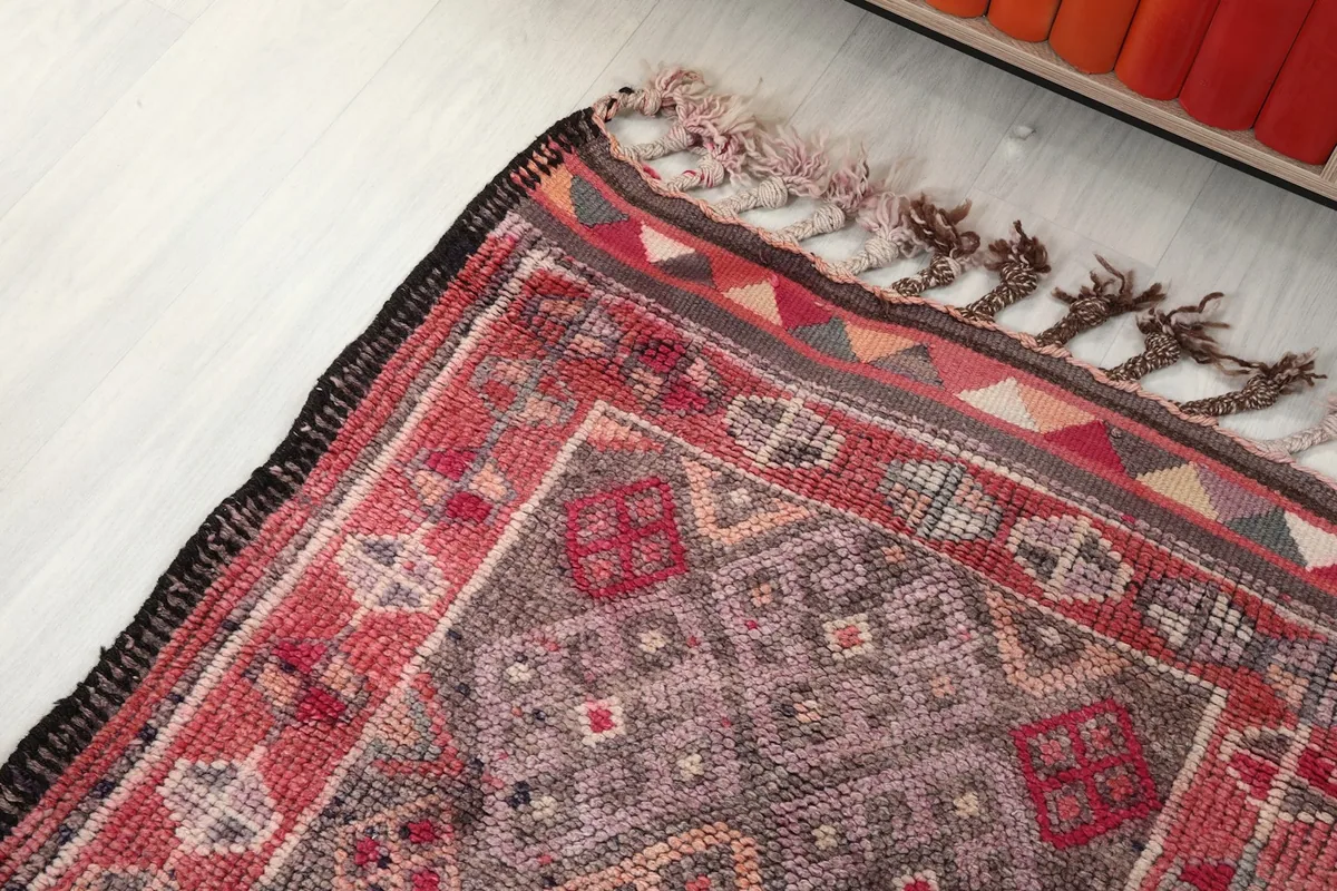 Overhead angle showing the rug's texture, fringe, and the blend of rose, gray, and brown tones