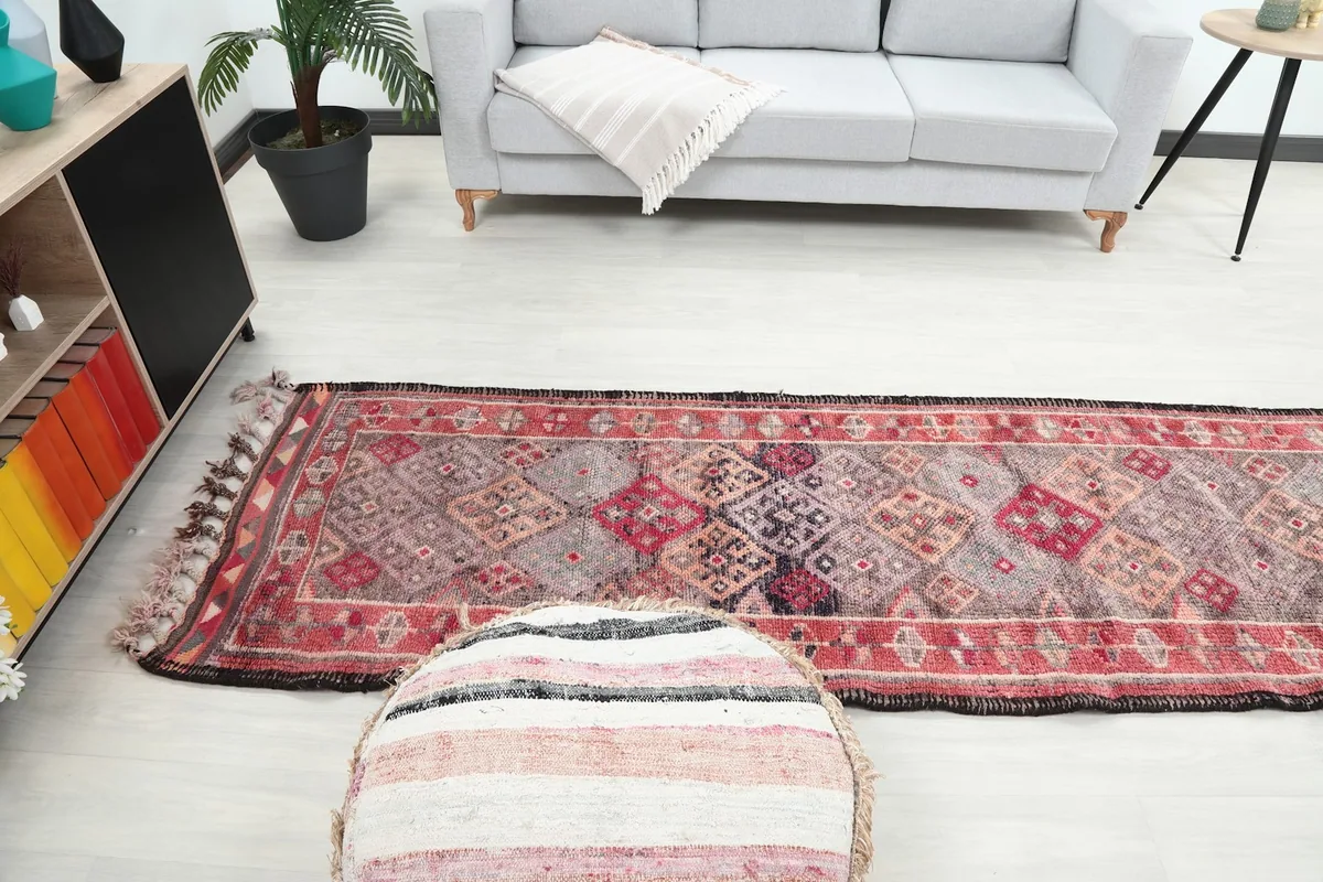 The runner rug leading towards a gray sofa, highlighting its length and placement in a room