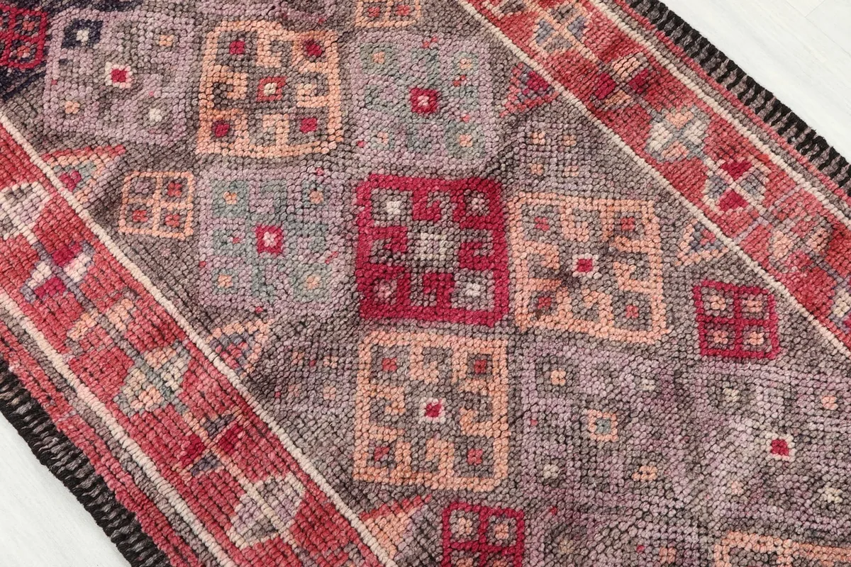 Close-up of the geometric patterns and varied color squares within the rug's field