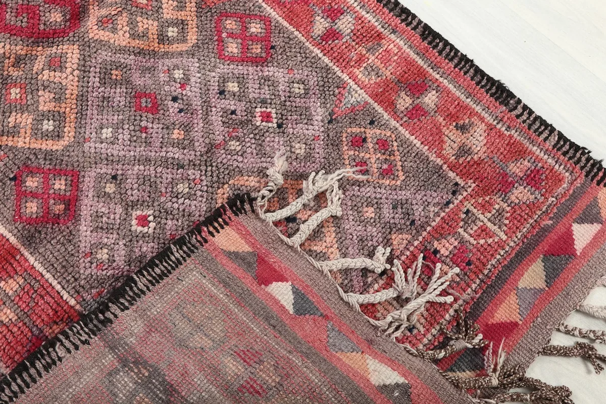 View of the rug's reverse side and pile, showing its hand-knotted construction and fringe