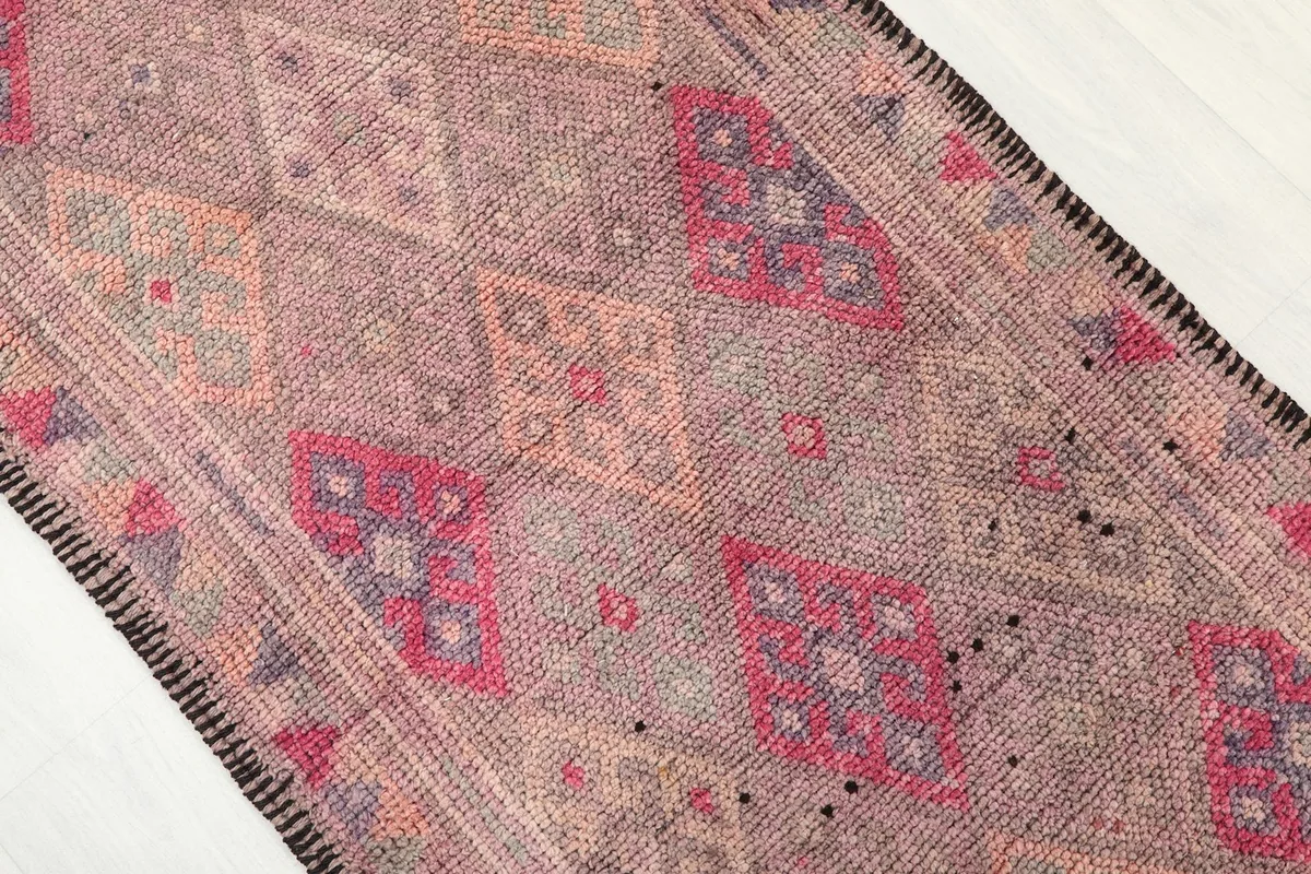 Close-up of the faded rose and beige geometric patterns on the vintage runner