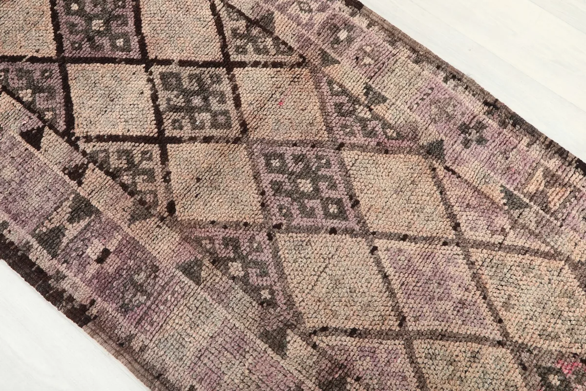 Angled close-up of the rug's central geometric patterns and color transitions, including purple and brown.