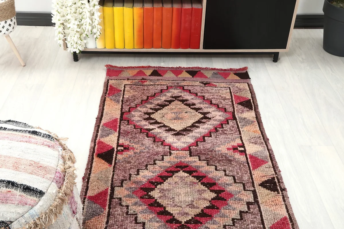 Overhead view of a section of the rose and gray geometric runner rug in a room setting