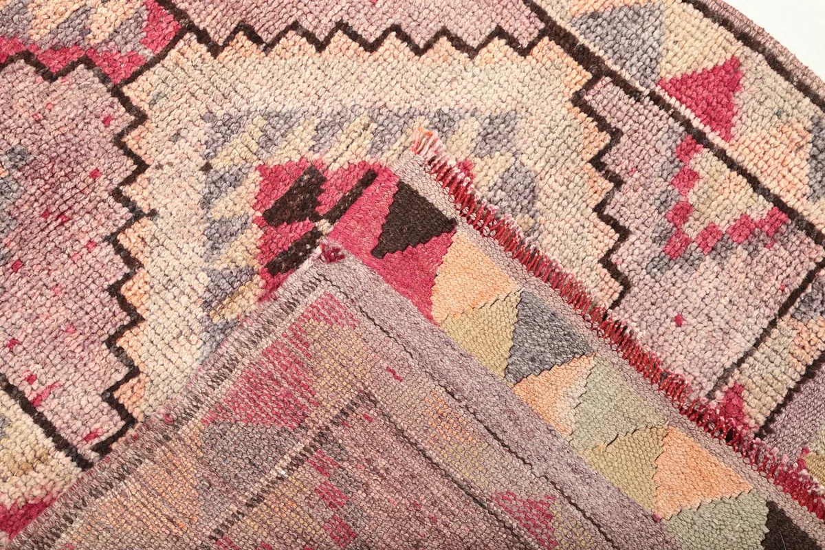 Folded corner showing the reverse side and hand-knotted cotton foundation of the runner