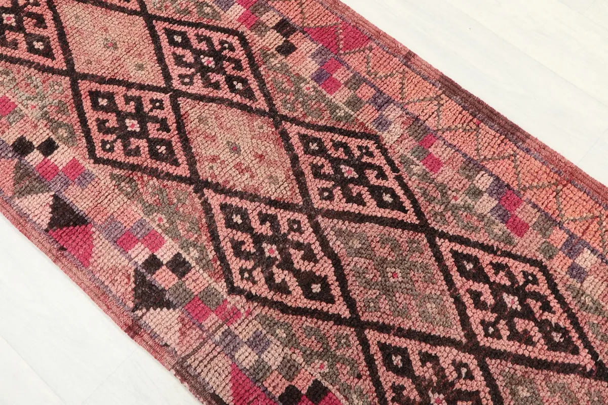 Close-up of the central geometric diamond motifs in brown and gray on the rose field of the runner.