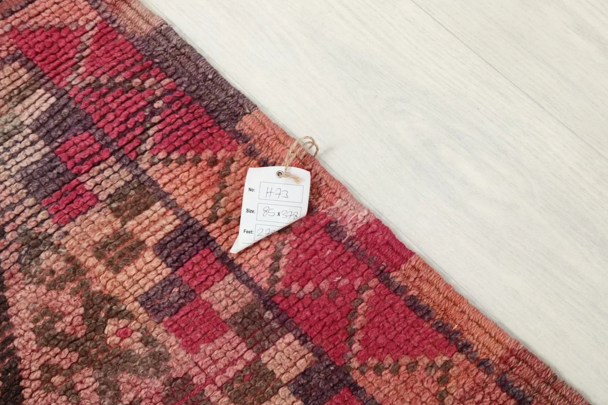 Detail of the rug with a product tag, showing the texture and color variations of the wool.