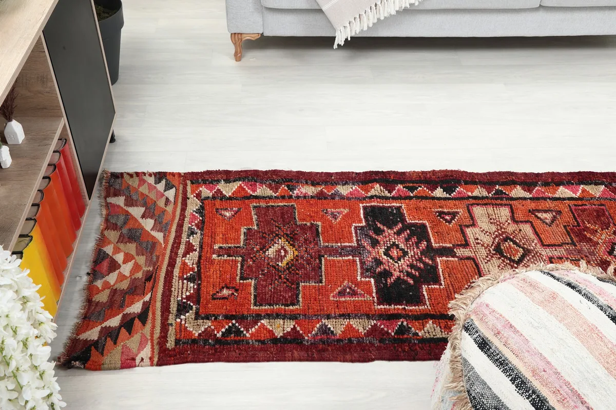 View of the runner rug extending down a hallway-like space with a sofa in the background