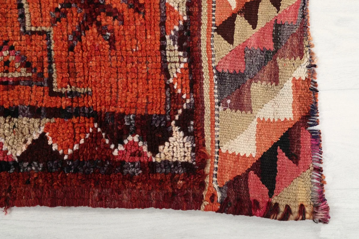 Close-up of the rug's border design with triangle patterns in rust, beige, and black
