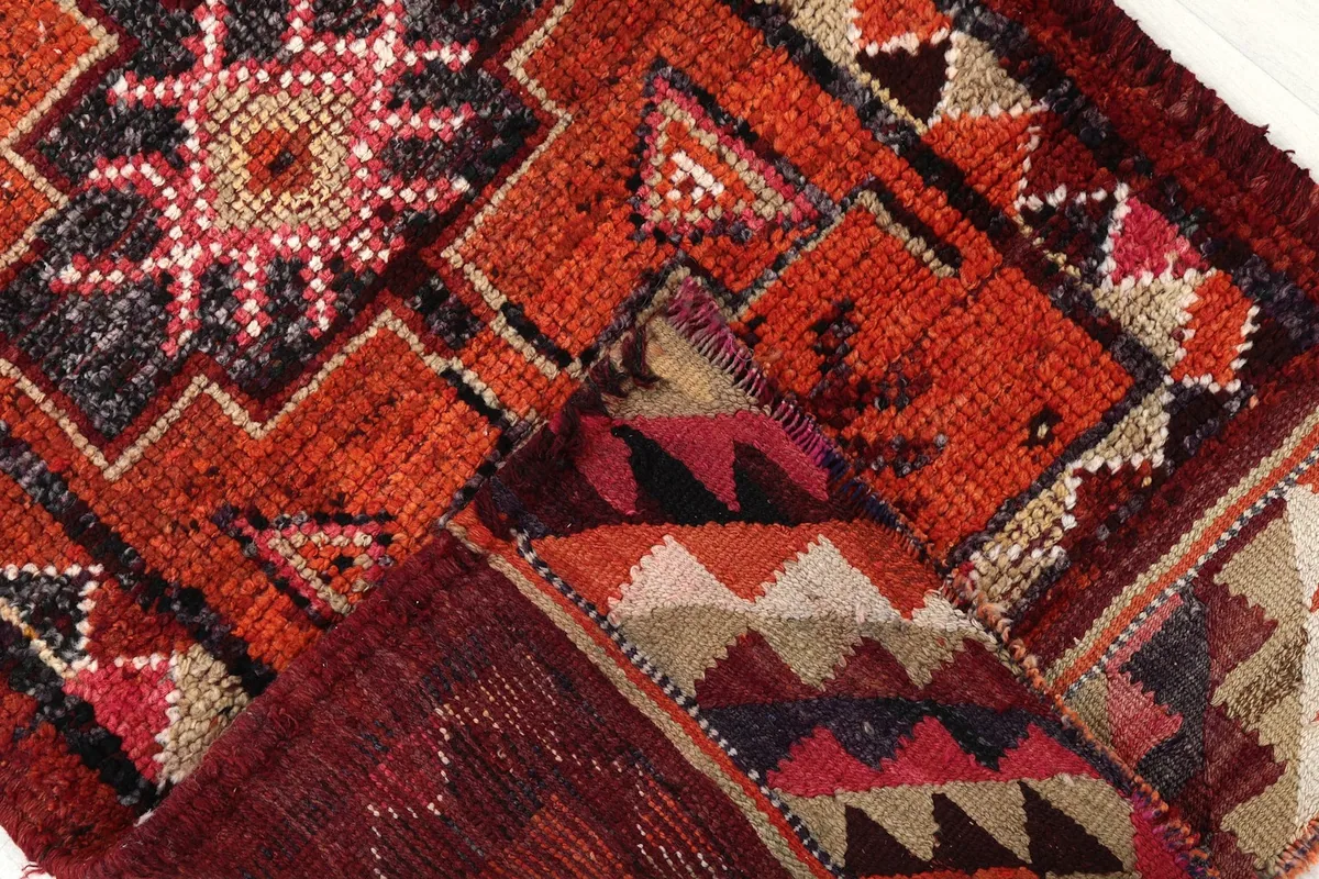 Folded corner of the rug revealing the cotton foundation and the reverse side of the knots