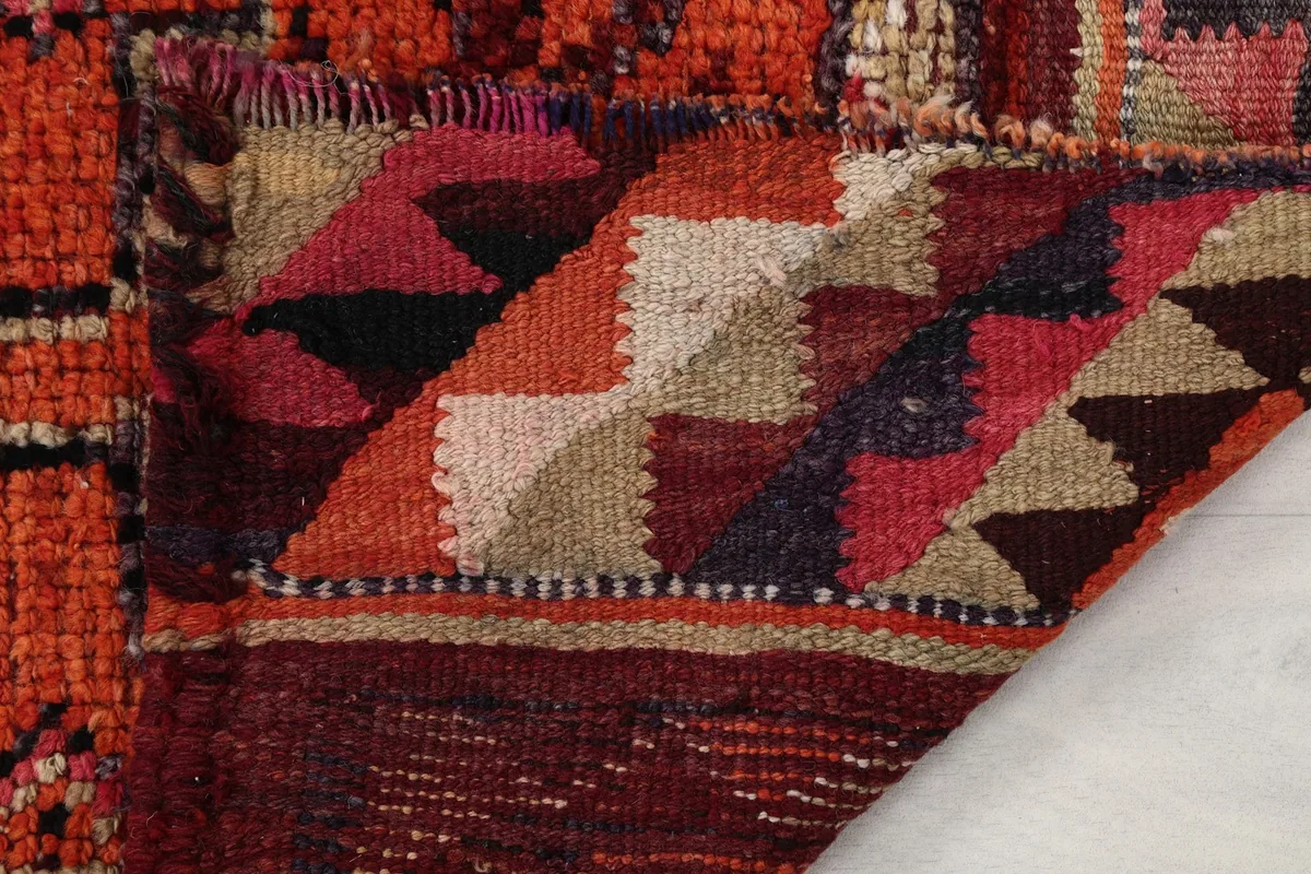 Detail of the rug's end, showing the flat-woven kilim section and the short, worn fringe