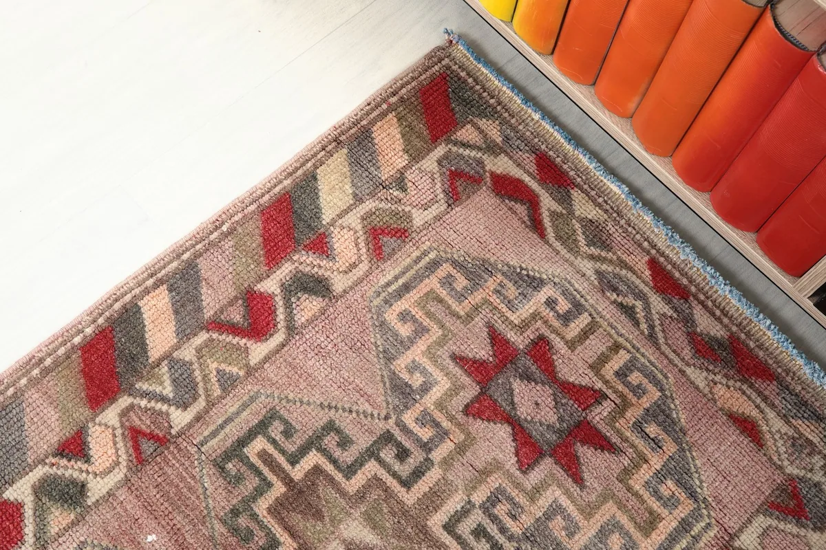 Corner detail of the rug showing the striped border and the rose main field with geometric design