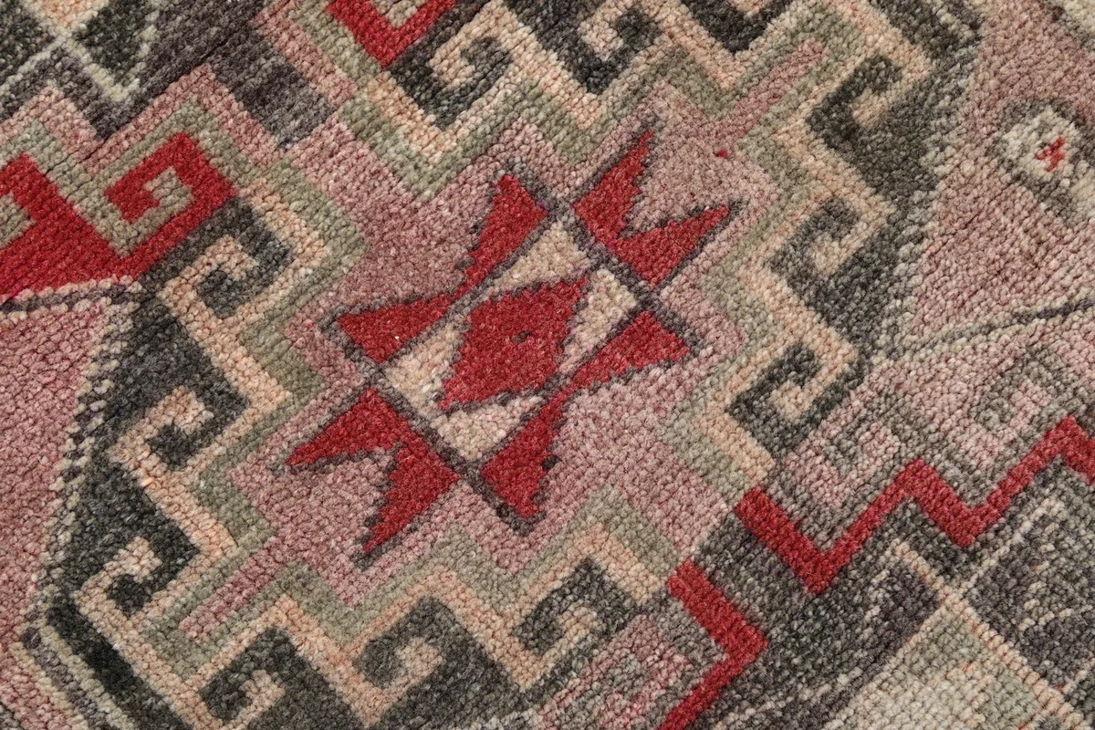 Texture close-up of the low wool pile, highlighting the red and tan geometric shapes
