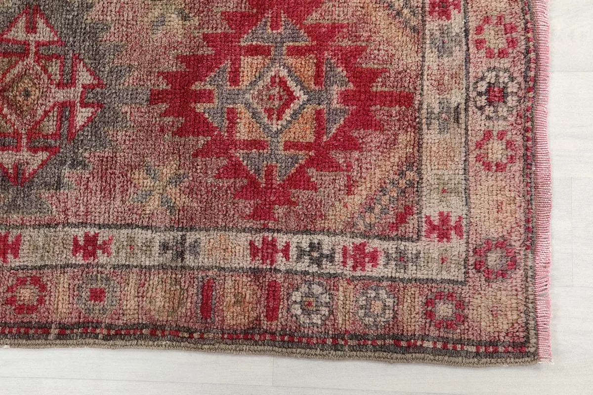 Detailed view of a red and gray geometric motif and a section of the border design on the runner.