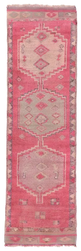 Full overhead view of a vintage rose tribal medallion runner rug on a white background.