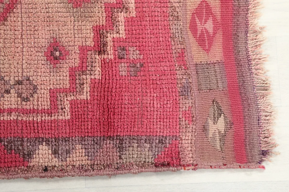 Detailed view of the rose rug's edge, showing the hand-knotted pile and subtle color variations.