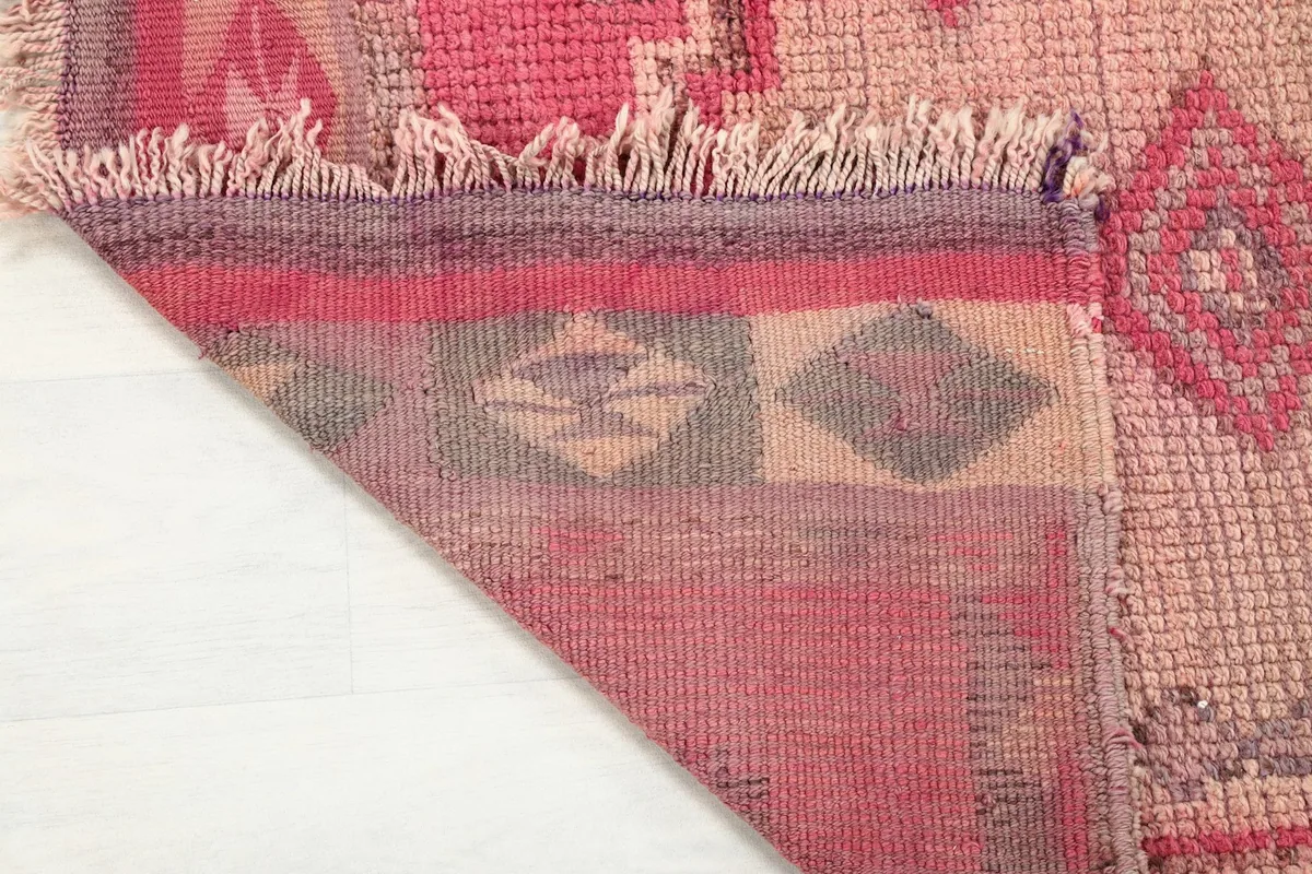 View of the back of the hand-knotted wool rug, revealing its cotton foundation and construction.
