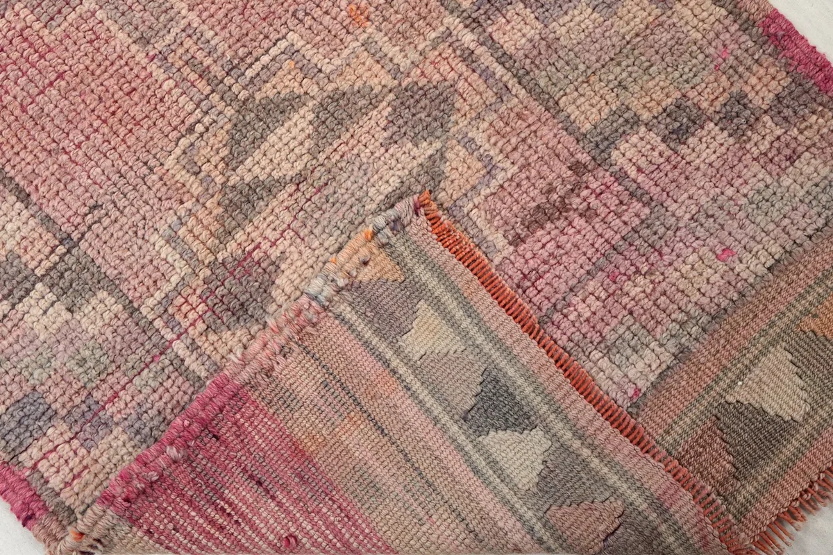 Flipped corner of the rug, showing the reverse side of the hand-knotted wool and cotton foundation