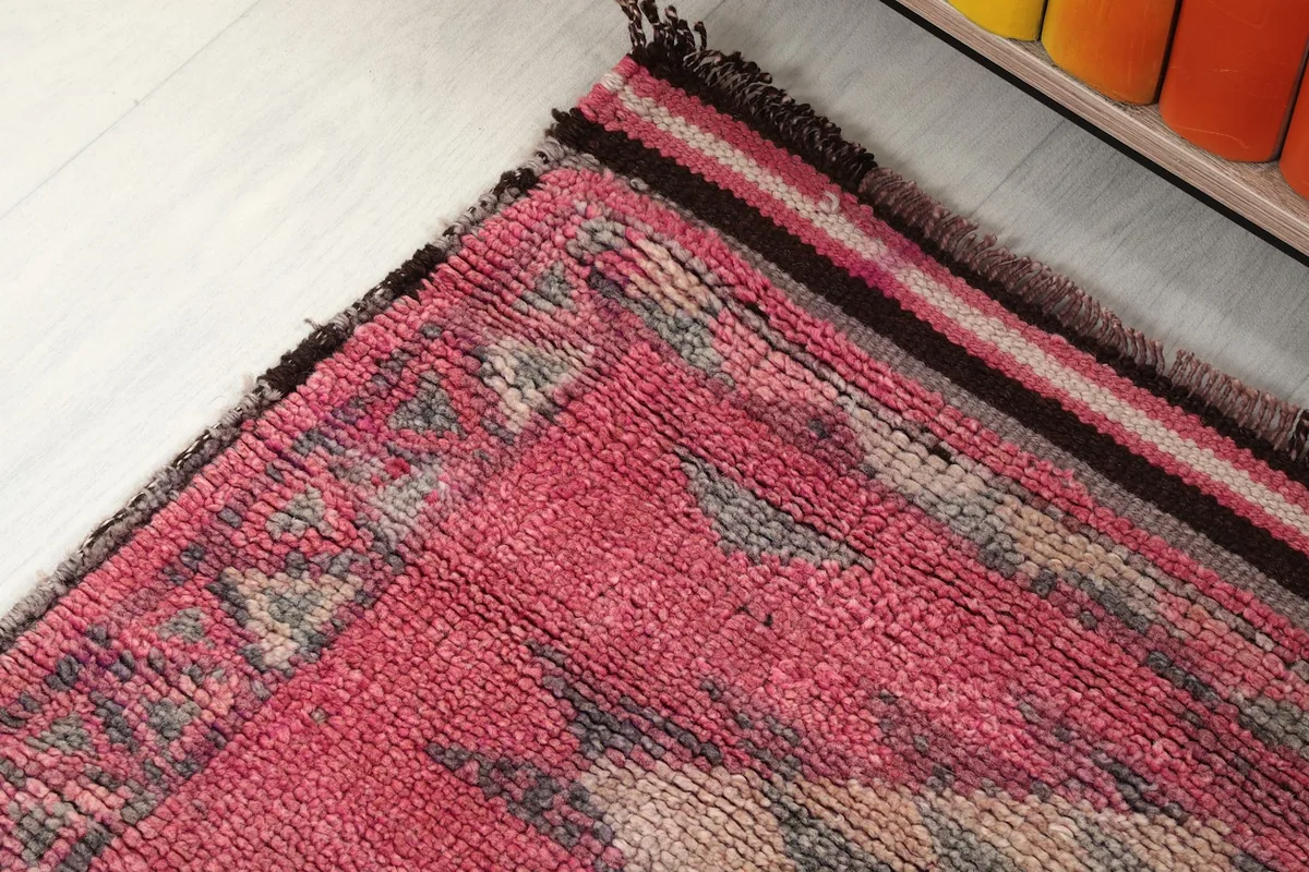 Close-up of the rug's end section, showing the rose color and dark border
