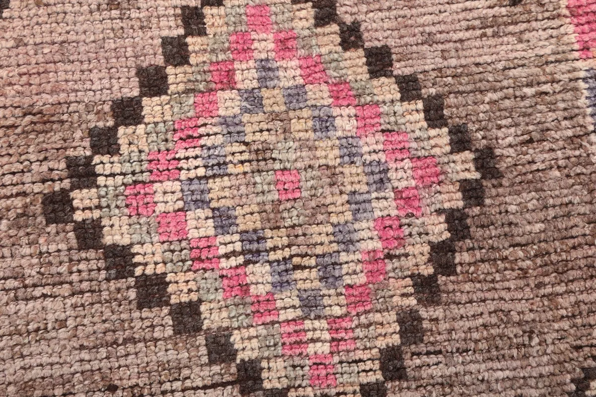 Close-up detail of a central pink and blue geometric diamond motif on the rug