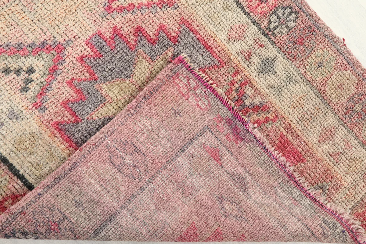 Folded corner of the Soft Rose Geometric Anatolian Runner, revealing the cotton foundation and hand-knotting.
