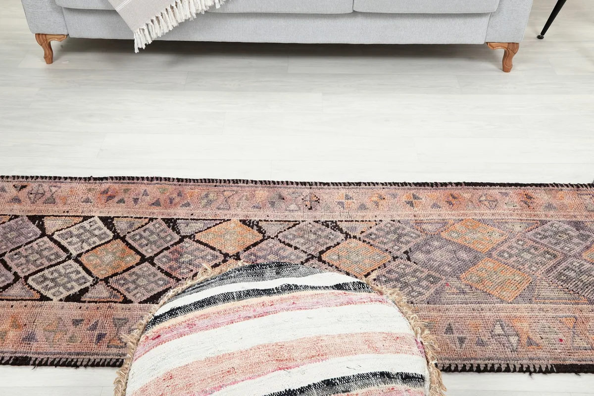 View looking down the length of the runner, with a decorative pouf in the foreground and a sofa in the distance.