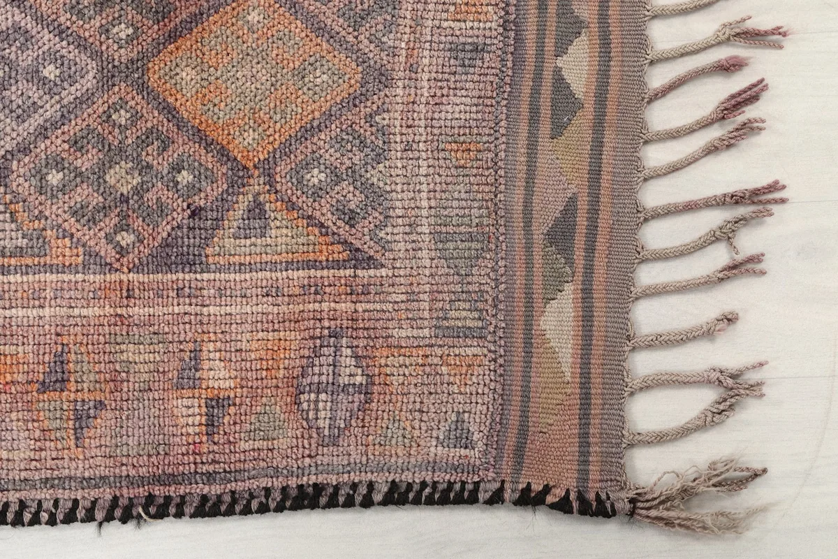 Detailed view of the runner's end, showing the fringe and the subtle color variations in the rose and gray border.