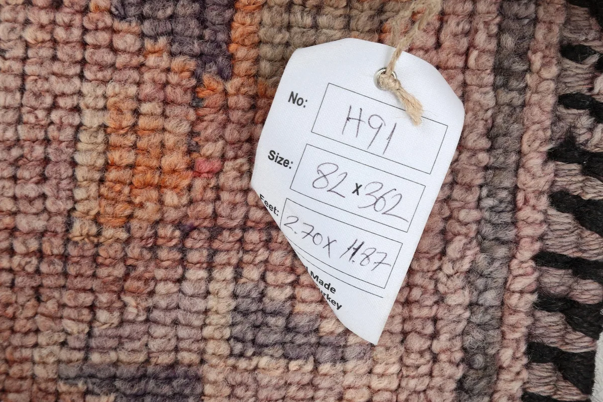 Close-up of the rug's surface with a tag displaying product information including dimensions and origin.