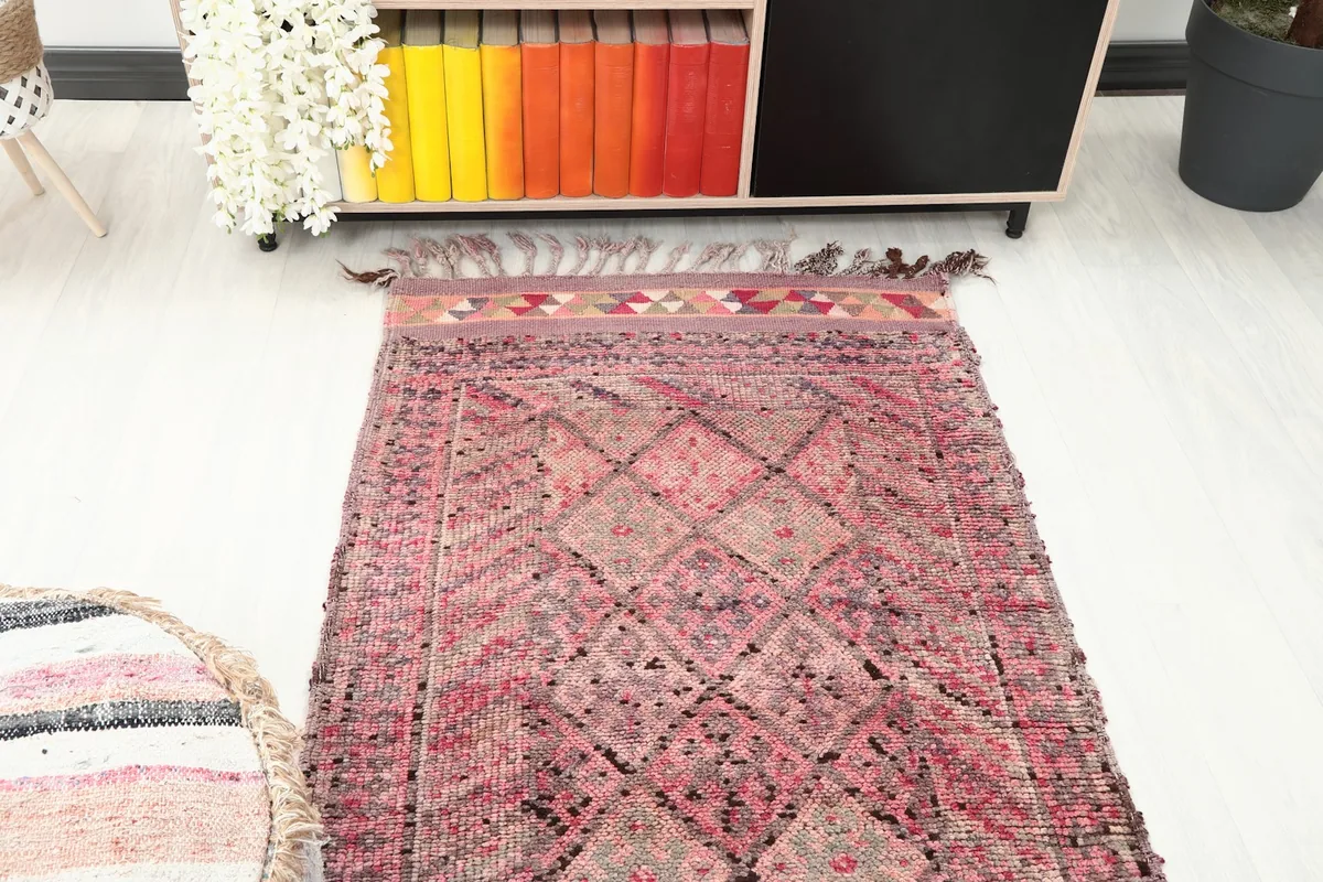 Overhead angle view of the rug's end, showing the geometric field and the colorful triangle border